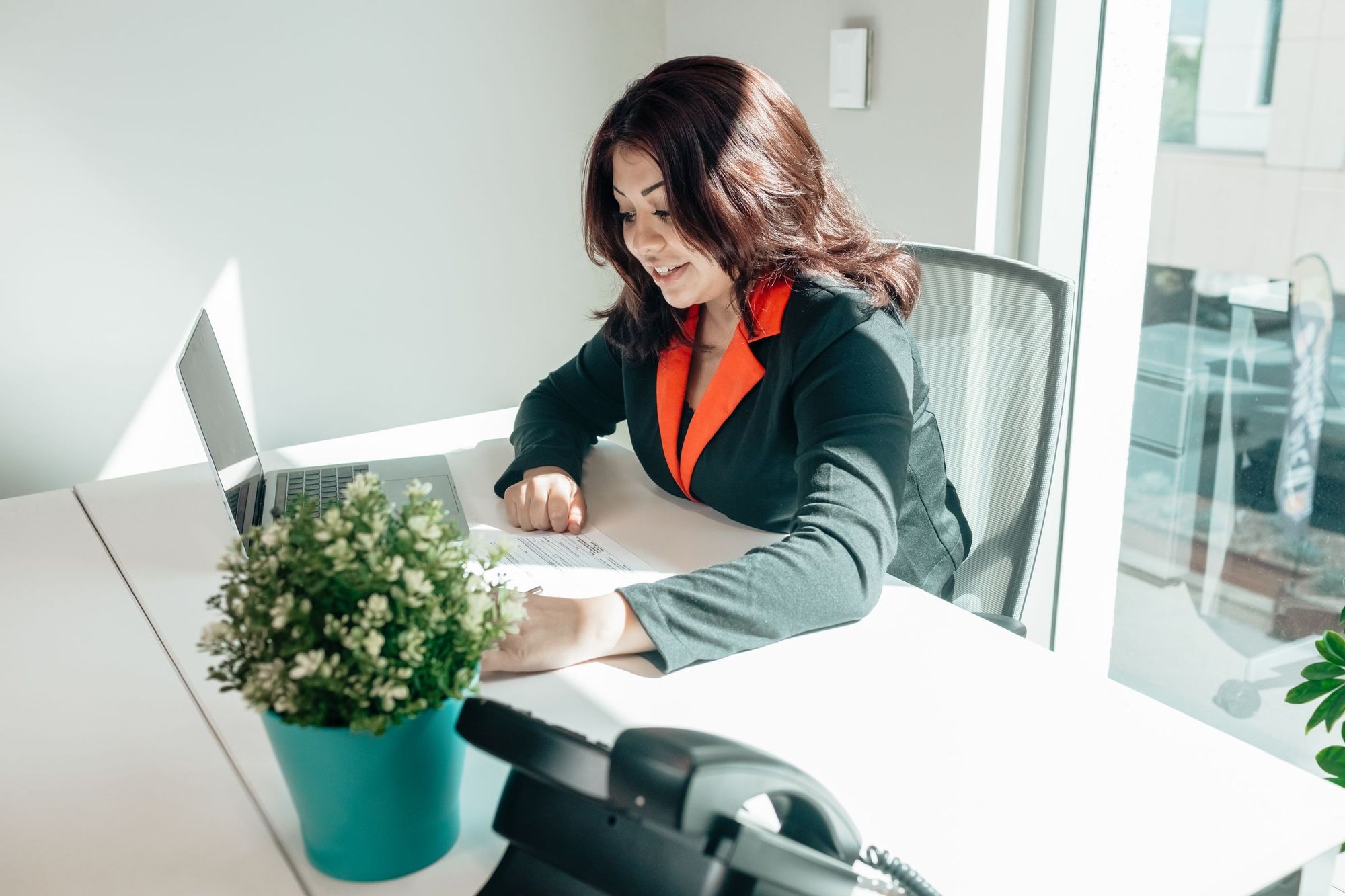 A woman smiling at her laptop in a bright office
